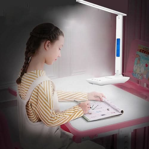 Child at desk using Lamp Plus 3 in 1 Lamp with phone charger, clock and thermostat while working on drawing