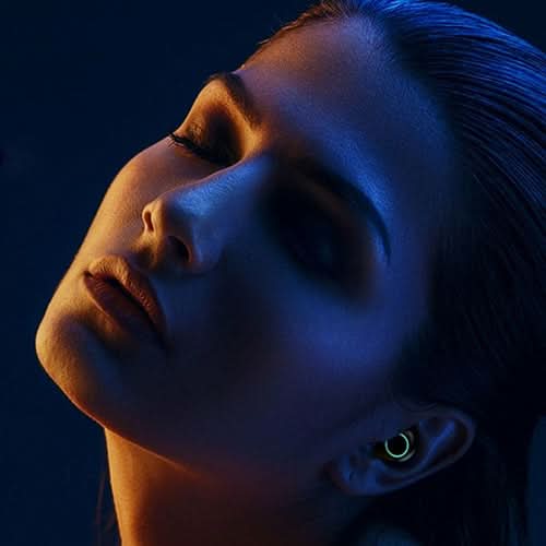 Side profile of person wearing True Twin 2 In 1 wireless headphone with glowing accent against blue background