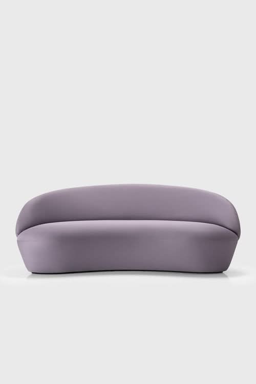Naïve Sofa with curved silhouette in muted purple upholstery, viewed from the side