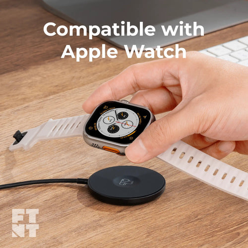 Magnetic wireless charger with a sleek black round base, charging an Apple Watch held above it, next to a white strap.