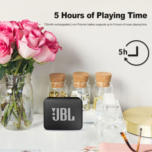 JBL GO 2 wireless Bluetooth speaker on white surface with flowers and decorative bottles