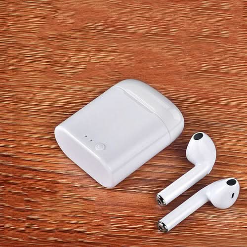 White wireless earbuds with charging case on wooden surface