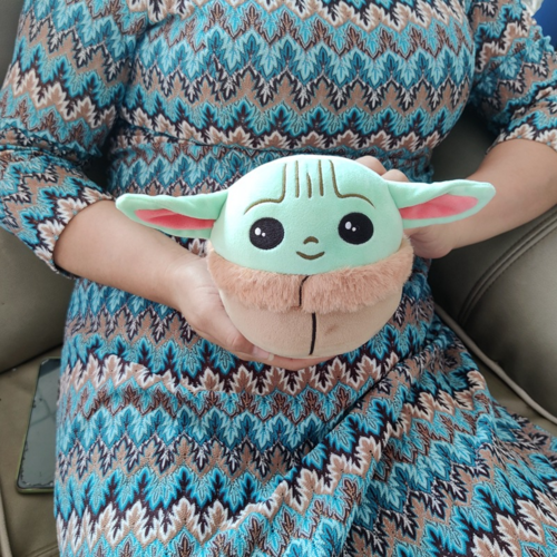 Disney Mandalorian Baby Yoda plush toy held in hands, mint green face with pink ears and brown fur chest detail