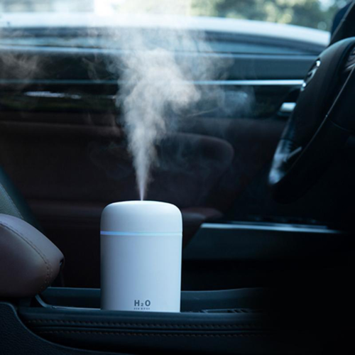 White portable humidifier diffuser with mist stream, placed on car dashboard
