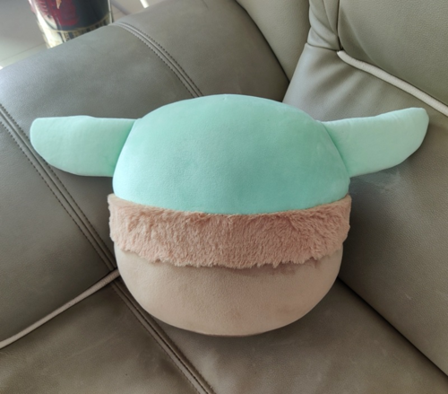 Disney Mandalorian Baby Yoda stuffed plush toy with mint-green head, fuzzy pink band, and beige body sitting on gray seat