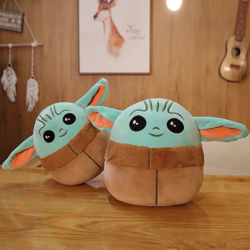 Two Baby Yoda plush toys with light blue heads, brown robes, and orange ears sitting on wooden surface